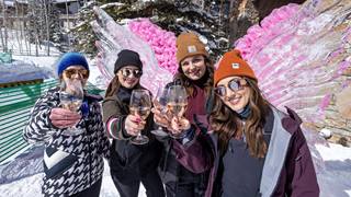 Group of women posing for photo holding wine glasses.
