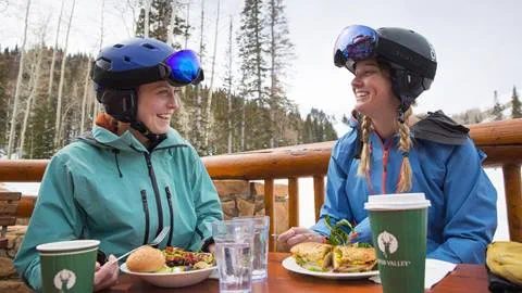 Two female guests eating on the deck of a day lodge at Deer Valley Resort