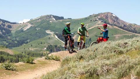 A Deer Valley bike coach talking to two guests
