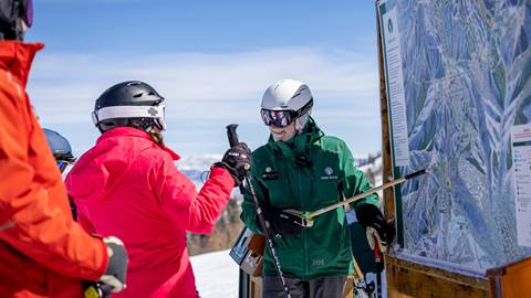 Deer Valley Mountain Host standing at map giving guests directions.