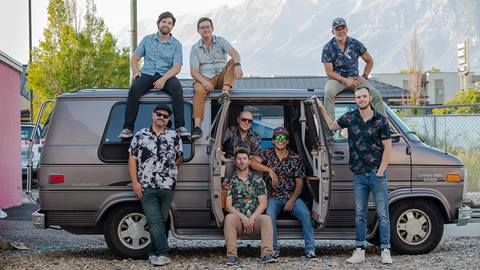 Bruzuca Band members sitting around a van.