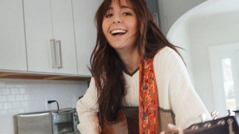 Musician, Hana Kamler, playing guitar in a kitchen.