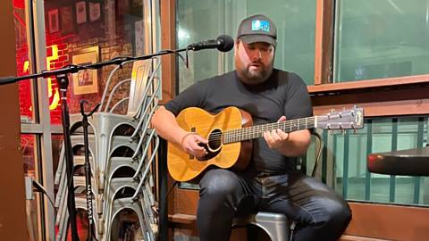 Musician, Mike Tam, playing a guitar at a concert venue.