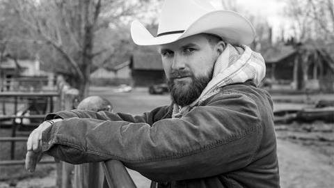 Country singer, Skylar Geer, leaning against a fence.