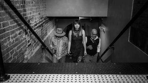 Band members from the Proper Way walking up a set of stairs towards a concert venue.