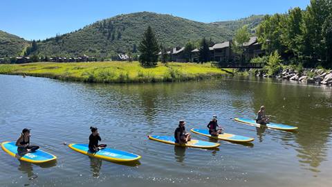 Guests sitting on five paddleboards on Pebble Beach at Deer Valley