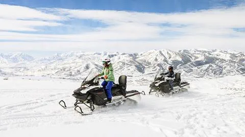 Two women on a snowmobiling tour with Summit Meadows Adventures through Deer Valley.