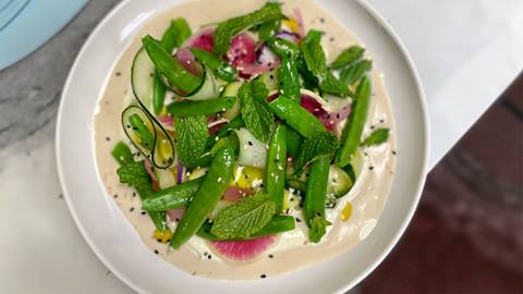 Fresh green salad with thinly sliced cucmber, sesame seeds, snow peas, mint and dressing