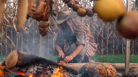 Chef Sarah Glover stoking a fire for a dinner she is preparing.