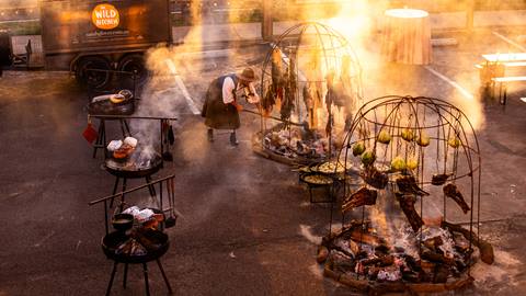 Chef Sarah Glover stoking a fire for a dinner she is preparing.