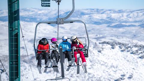 Guests chatting while riding chairlift at Deer Valley on a bluebird day.