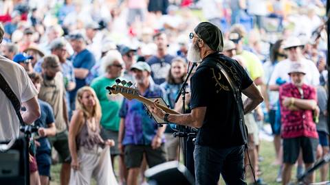 Musician singing on Deer Valley summer amphitheater stage overlooking crowd.