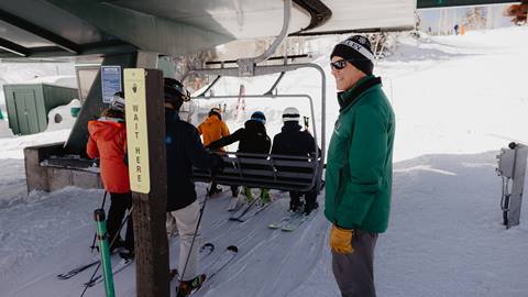 Deer Valley lift operator helping guests get on a chairlift.