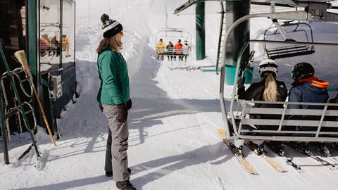 Deer Valley lift operator helping guests get on a chairlift.