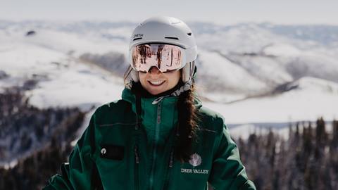 Deer Valley mountain host smiling at camera with expansive view of Deer Valley in the background