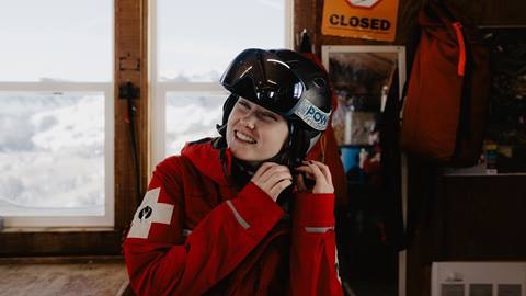 Deer Valley Ski Patrol team member putting on their helmet.