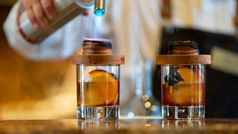 Bartender adding smoke to whiskey.