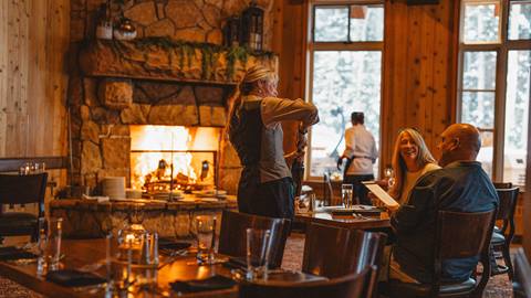 Deer Valley staff opening wine for couple at Fireside Dining.