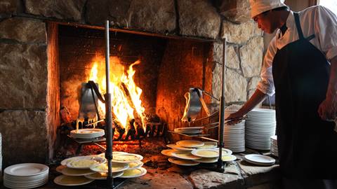 A cook watches closely as the raclette melts by the fire.