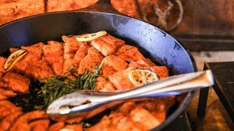 Salmon topped with lemon cooking in cast iron skillet.