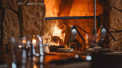 Raclette cheese melting at fireplace.