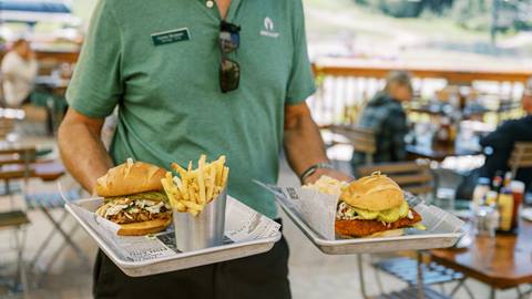 Deer Valley staff member holding two trays of food on the Royal Street Cafe deck during the summer.