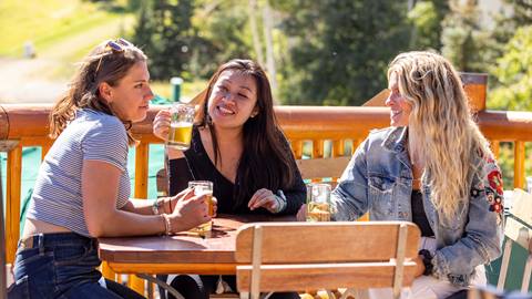Three women drinking beer on the Royal Street Cafe deck during the summer.