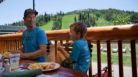 Father and son eating on the Royal Street Cafe deck during the summer.