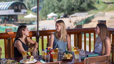 Three guests eating on the Royal Street Cafe deck during the summer.