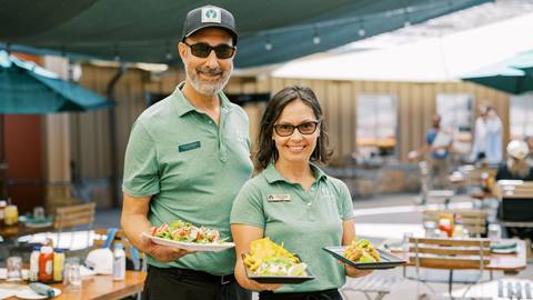Deer Valley staff members holding trays of food on the Royal Street Cafe deck during the summer.