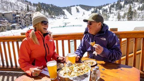 Couple enjoying après-ski outside at Deer Valley's Snow Park Lodge.