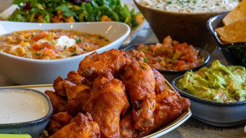 Buffalo wings displayed next to a bowl of guacamole.