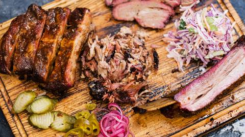 Deliciously grilled ribs and tenderly sliced steak elegantly arranged on a rustic wooden cutting board.