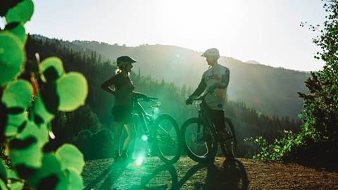 Couple standing by their mountain bikes.