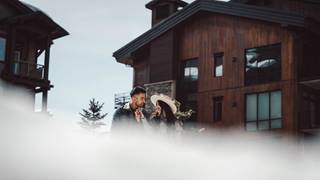 Couple standing outside of luxury lodging property at Deer Valley in the winter.