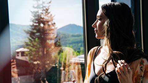 Woman drinking wine by a window at Deer Valley in the summer. 