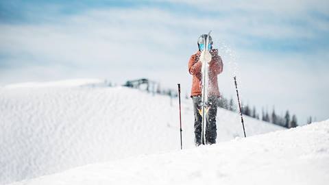 Guest is dusting snow off of his skis.