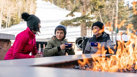 Mom sitting by firepit with her children.