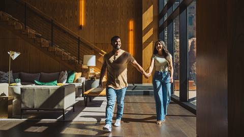 Couple holding hands walking through lobby of high-end lodging property