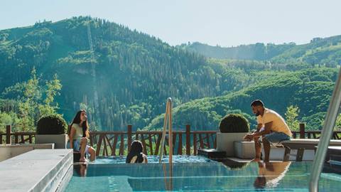 Parents sitting by pool with kids at One Empire Pass