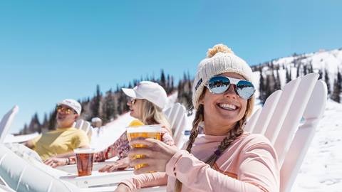 Three skiers drinking beer and enjoying après ski in the spring at Deer Valley.