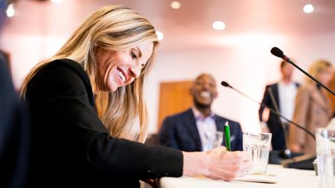 Woman signing documents during a conference meeting.