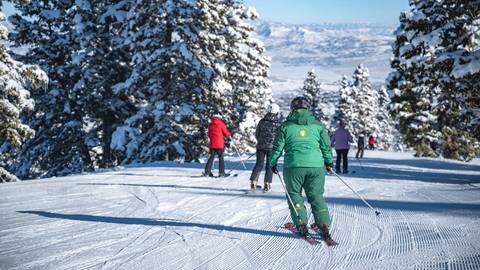 Deer Valley ski instructor skiing with adult group lesson students.