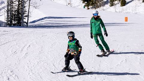 Deer Valley ski instructor teaching young boy to ski.