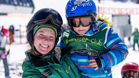 Deer Valley ski instructor smiling with child.