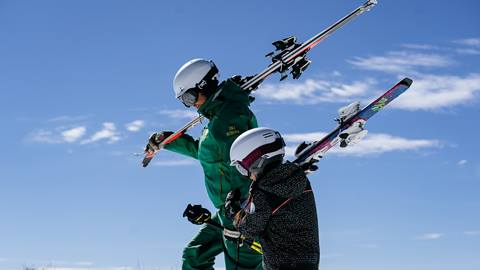 Deer Valley Ski Instructor and student carrying skis.