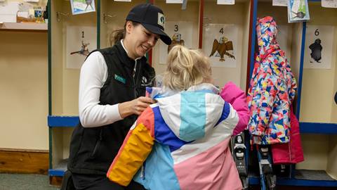 Deer Valley ski instructor helping young girl get ready for ski lesson.