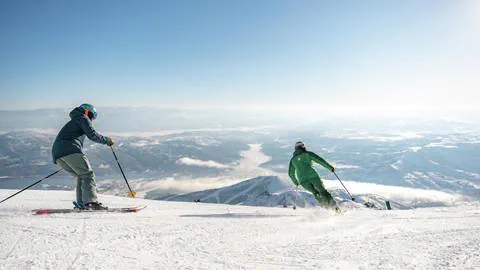 Man skiing behind Deer Valley Ski Instructor.