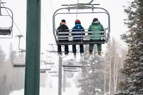 Deer Valley ski instructor and teenagers on chairlift during ski lesson.