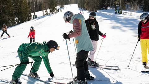 Deer Valley ski instructor helping teenager with his skis.